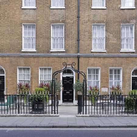 伦敦 巴比肯客房酒店 外观 照片 The photo shows a row of three-story brick buildings, featuring a classic design with large windows and decorative ironwork. The buildings are painted in a muted yellow-brown color, typical of older urban architecture. In front of the buildings, ther