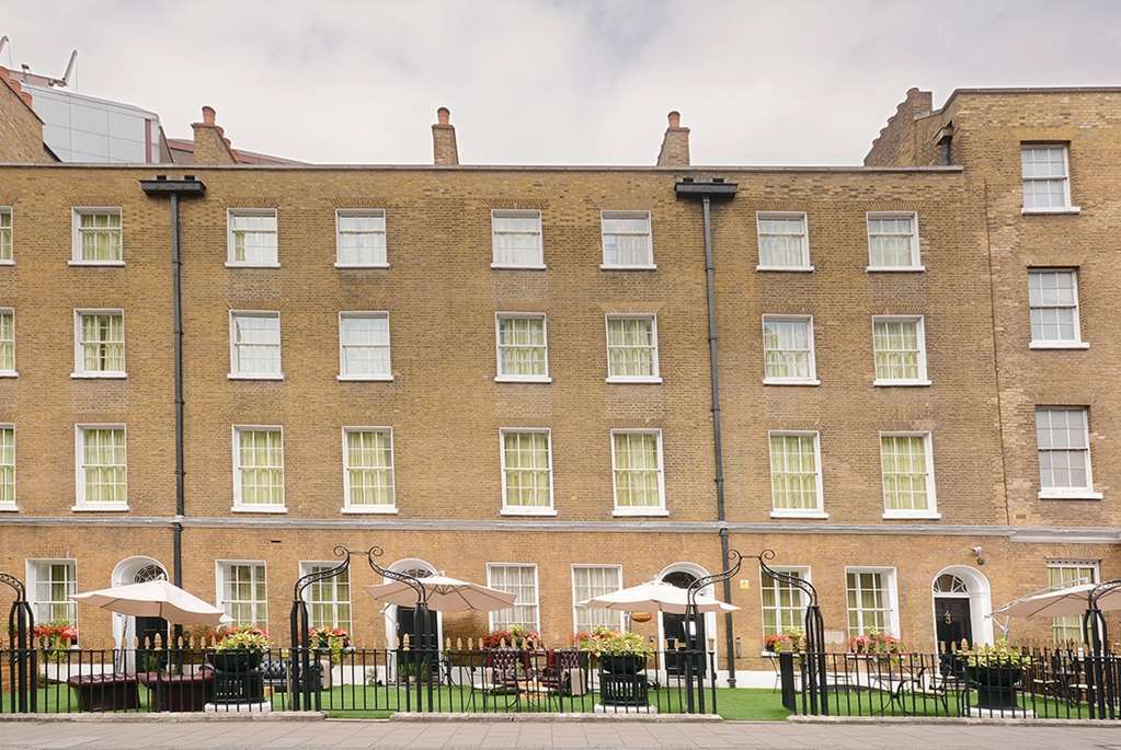 伦敦 巴比肯客房酒店 外观 照片 The photo shows a brick building with several windows on its facade. The structure appears to be three stories tall, featuring a symmetrical design with multiple windows that have white frames. In front of the building, there is a landscaped area wit