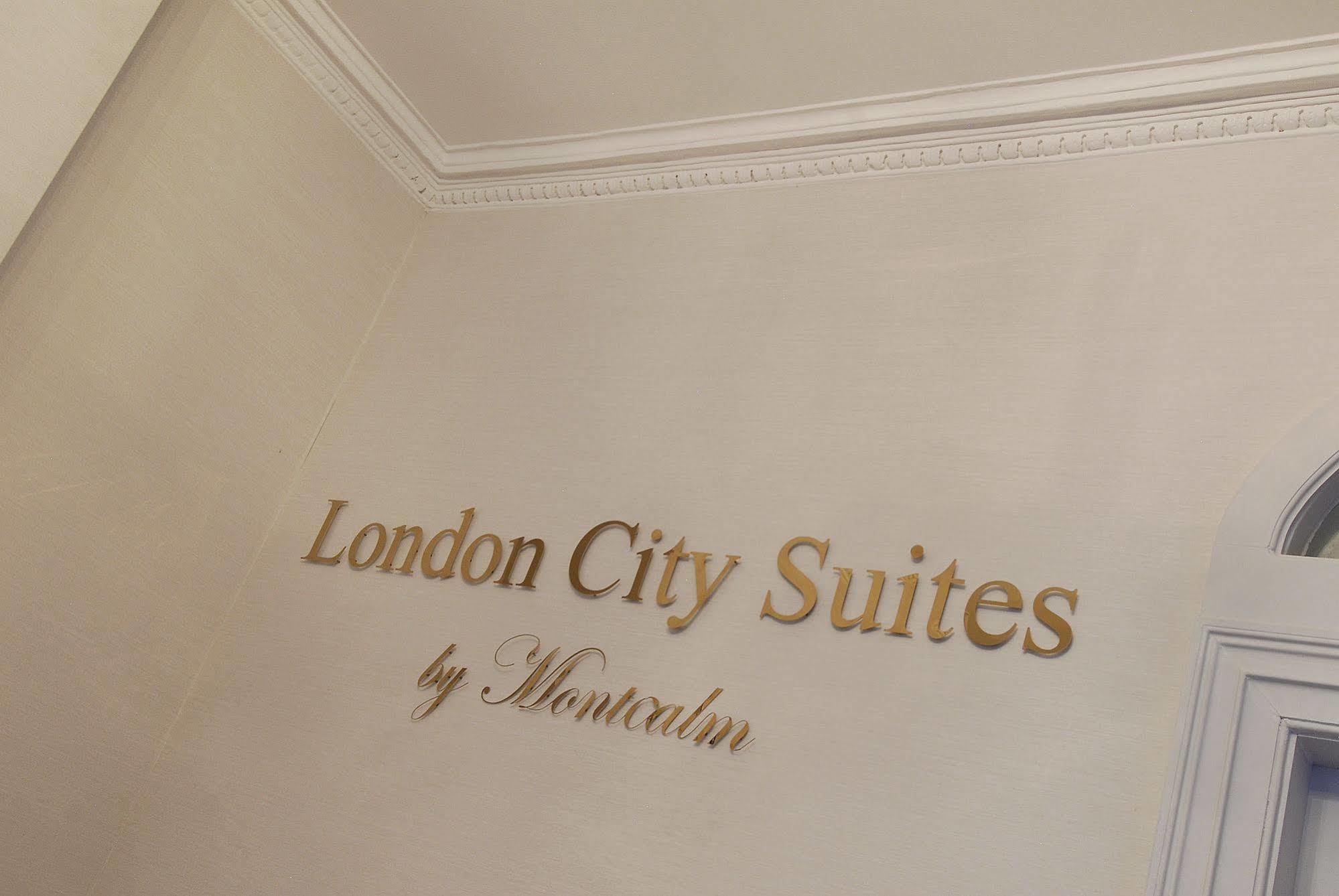 伦敦 巴比肯客房酒店 外观 照片 The photo shows a wall display featuring the text "London City Suites" in a bold, gold-colored font. Below that, the words "by Montcalm" are written in a smaller, elegant style. The background appears to be a neutral-colored wall, possibly in a hotel