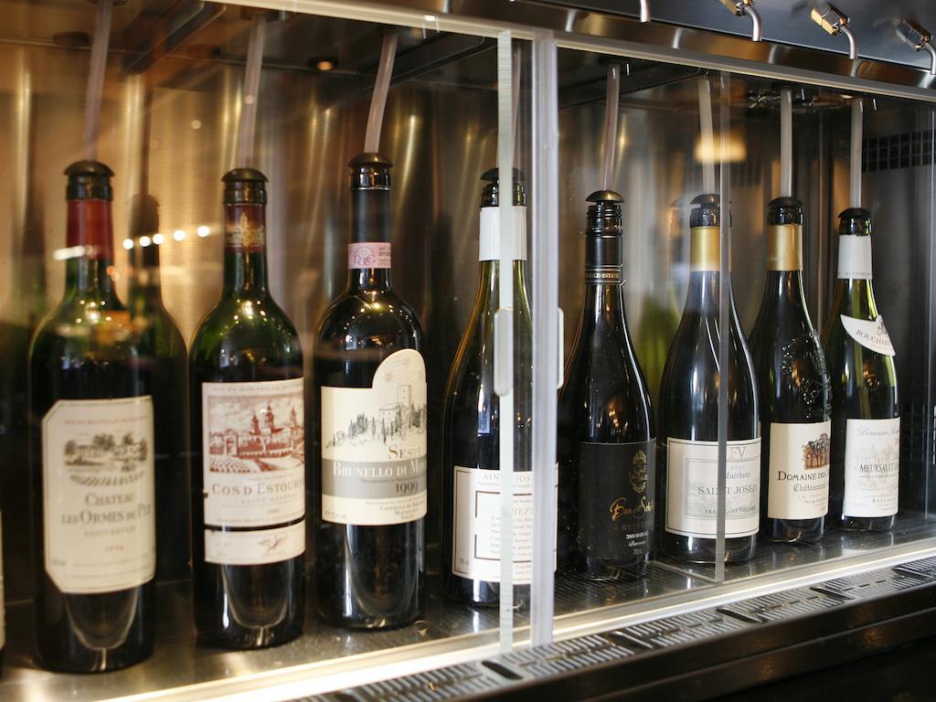 伦敦 巴比肯客房酒店 外观 照片 The photo depicts a selection of wine bottles displayed in a wine fridge or cooler. The bottles are lined up behind a glass panel, showcasing various types of wine, likely including both red and white varieties. Each bottle has a distinctive label, i