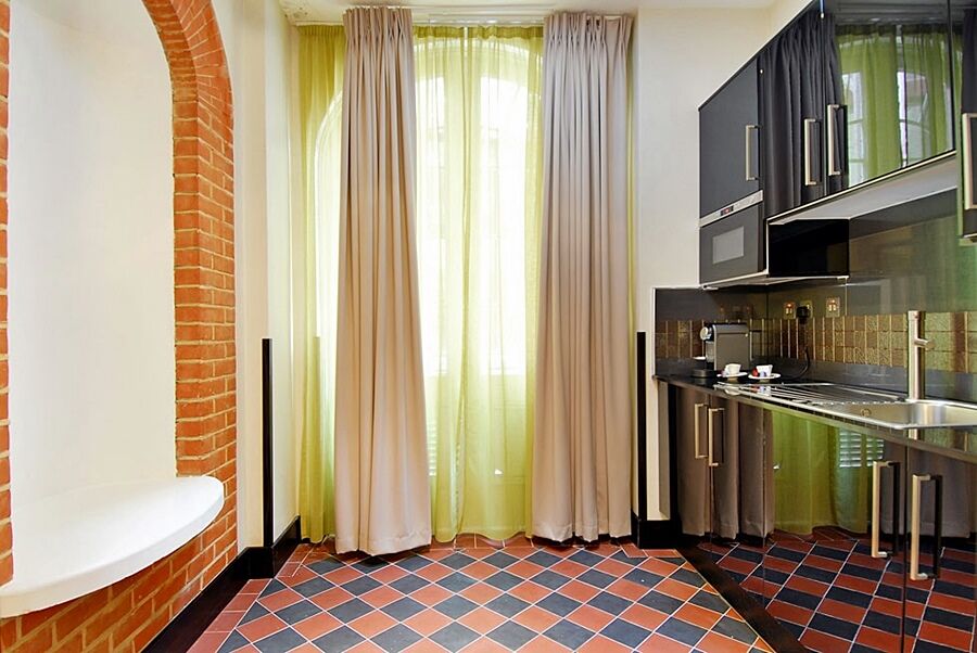 伦敦 巴比肯客房酒店 外观 照片 The photo shows a kitchen area with modern design elements. There are large, light-colored curtains hanging from the windows, allowing natural light to filter in. The walls are partially exposed brick, giving a warm texture to the room. The flooring 